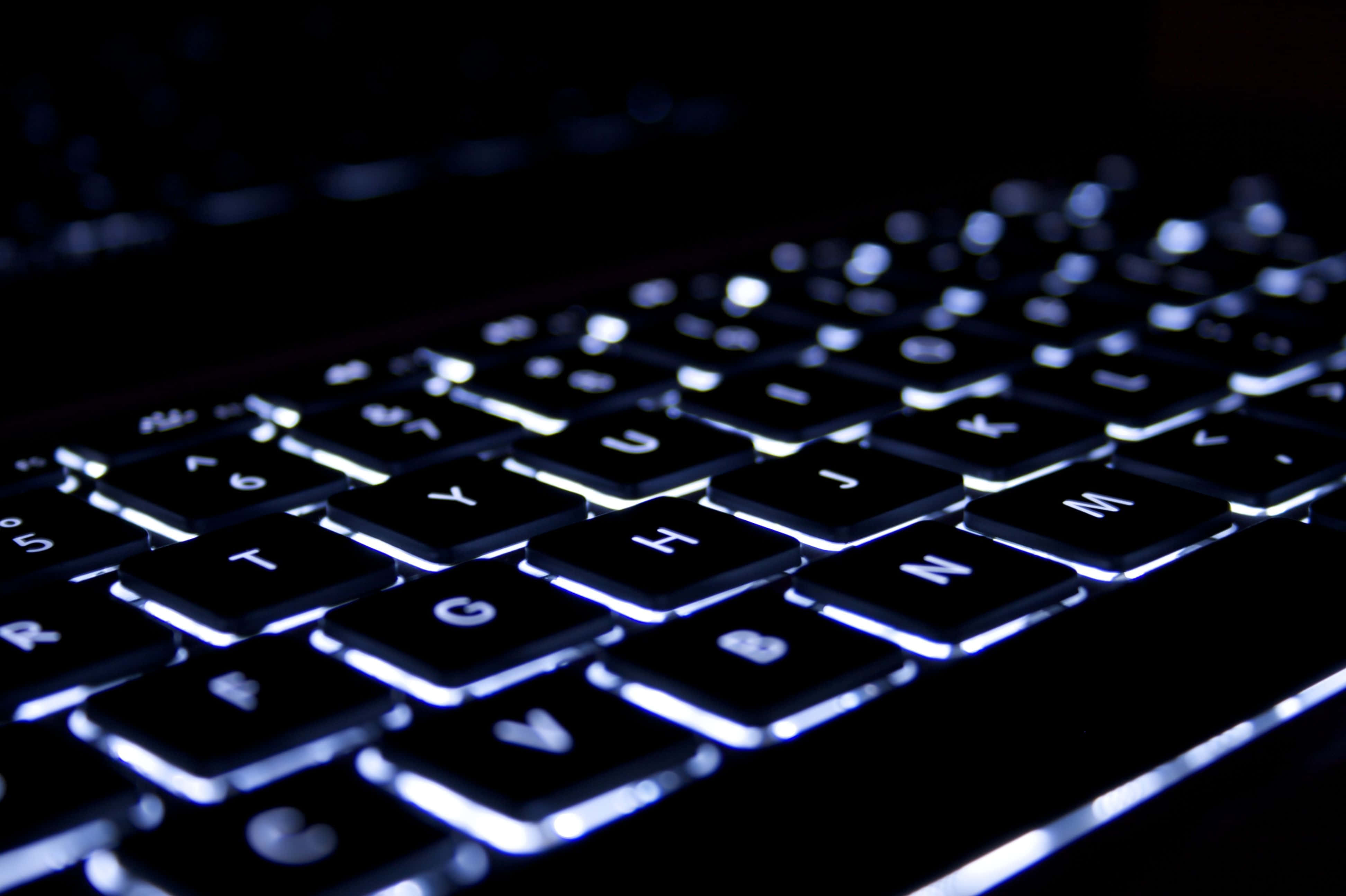 Gaming Keyboards 桌布 壁紙 — 黑色鍵盤特寫，白色背光在黑暗背景中發光。