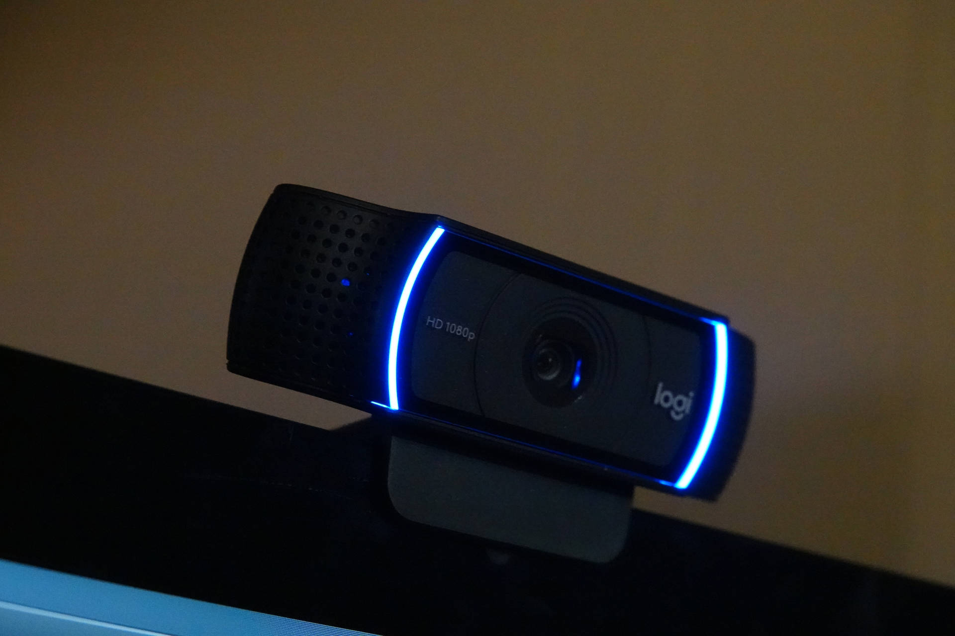 在低光環境下，顯示器上的黑色Logitech網絡攝像頭帶有藍色燈光。