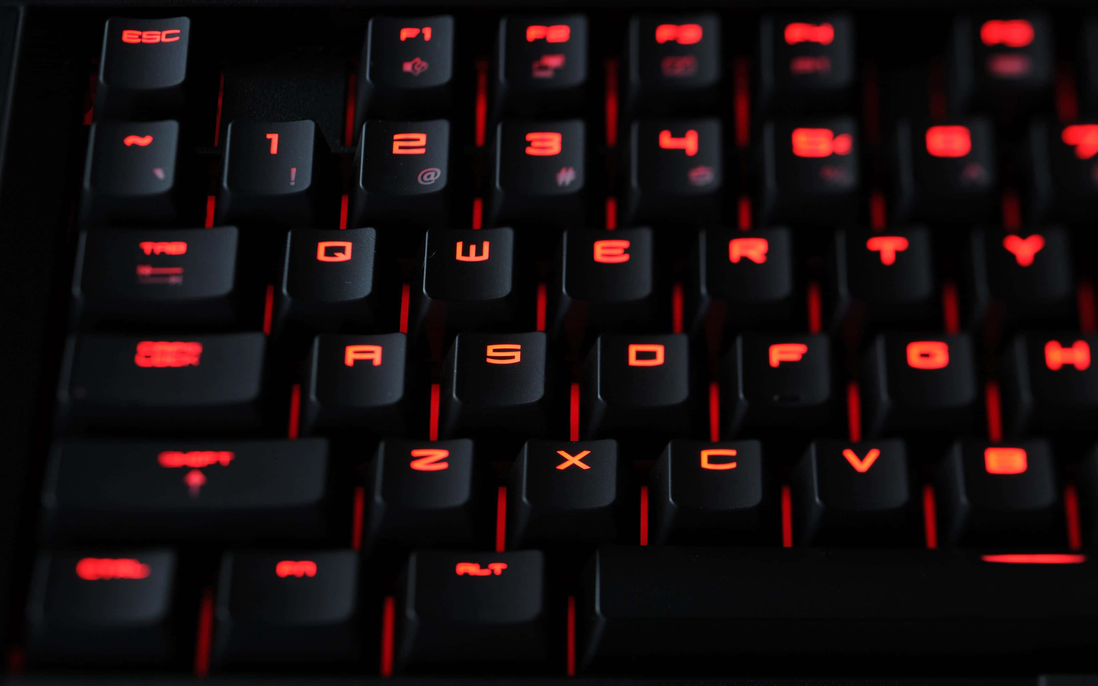 Gaming Keyboards 桌布 壁紙 — 黑色電競鍵盤特寫，按鍵在黑暗環境中發出紅色背光。
