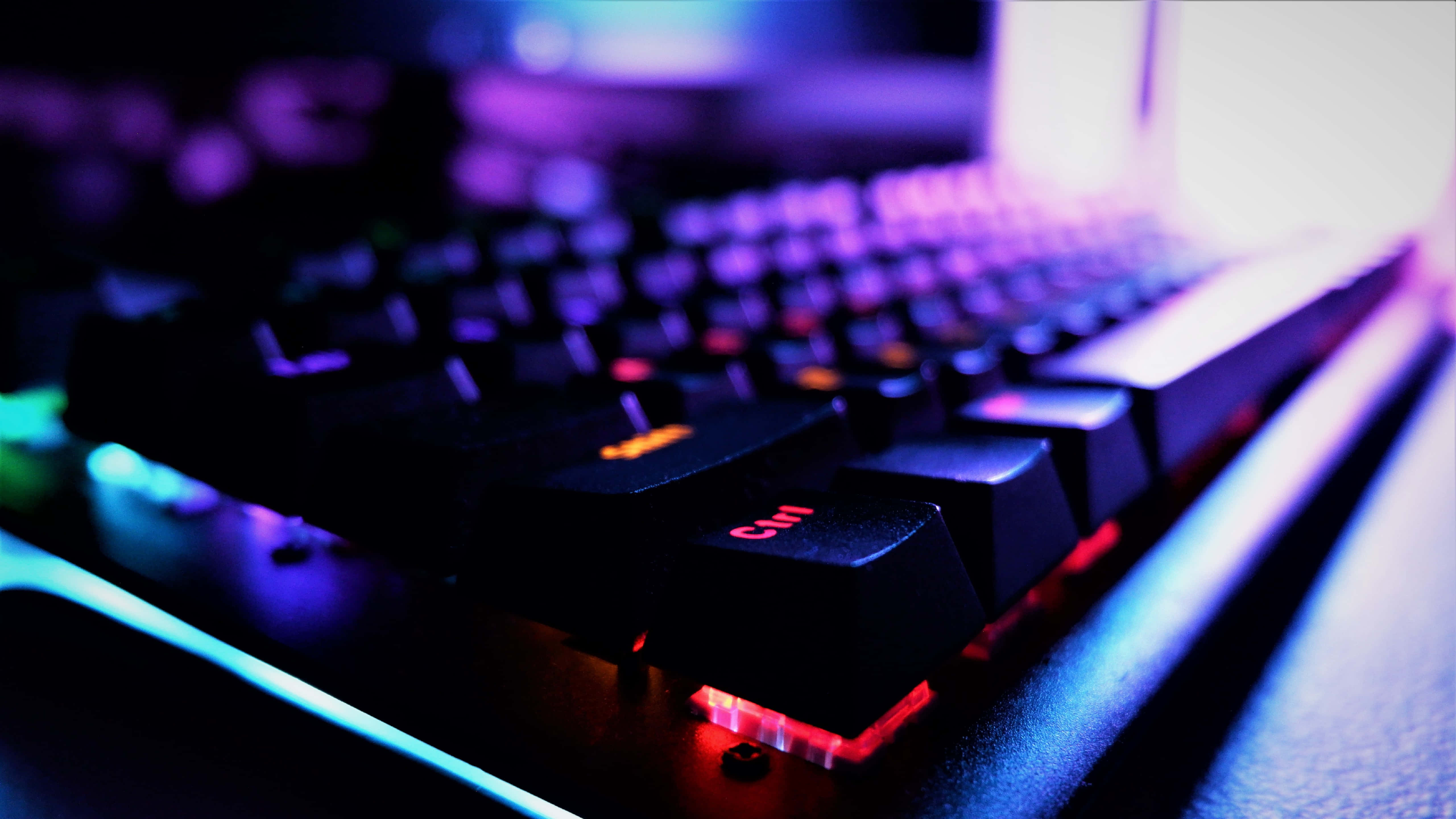 Gaming Keyboards 桌布 壁紙 — 黑色電競鍵盤的特寫，帶有充滿活力的紫色、藍色和紅色RGB背光。