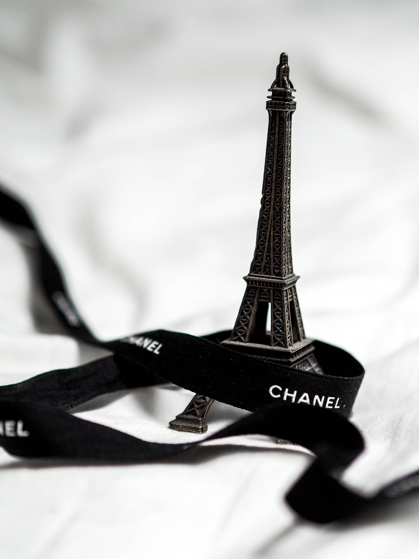 微型艾菲爾鐵塔模型在黑色 Chanel 絲帶上，襯以白色布料。
