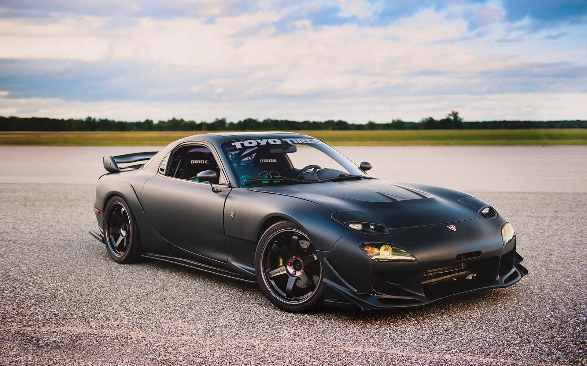 啞光黑色萬事得RX-7跑車在碎石路上，夕陽時分。