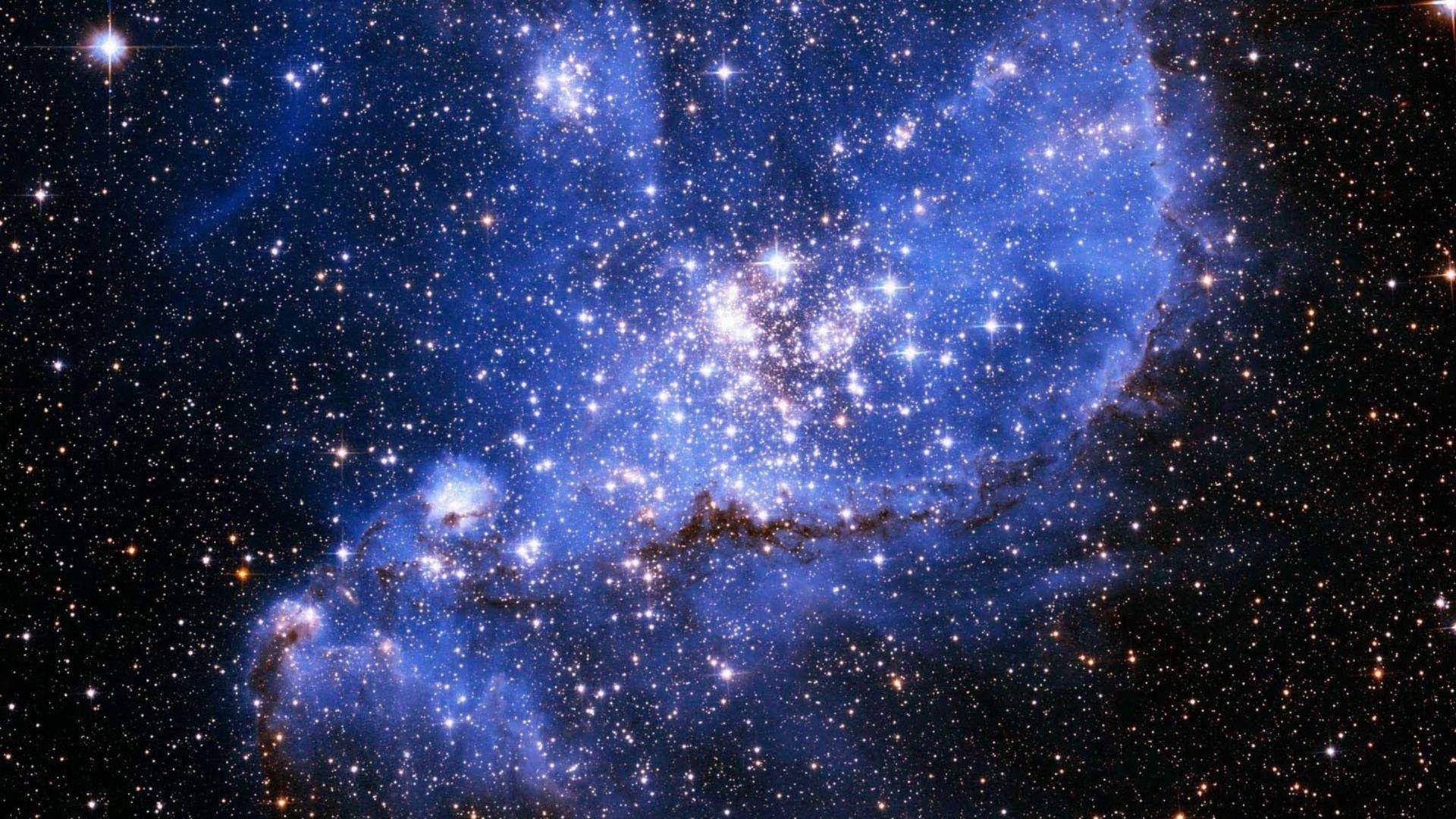 黑藍星系 壁紙 — 令人嘆為觀止的景象：一個發光的藍色星雲，充滿無數閃爍的星星，映襯著深邃的黑色宇宙虛空。