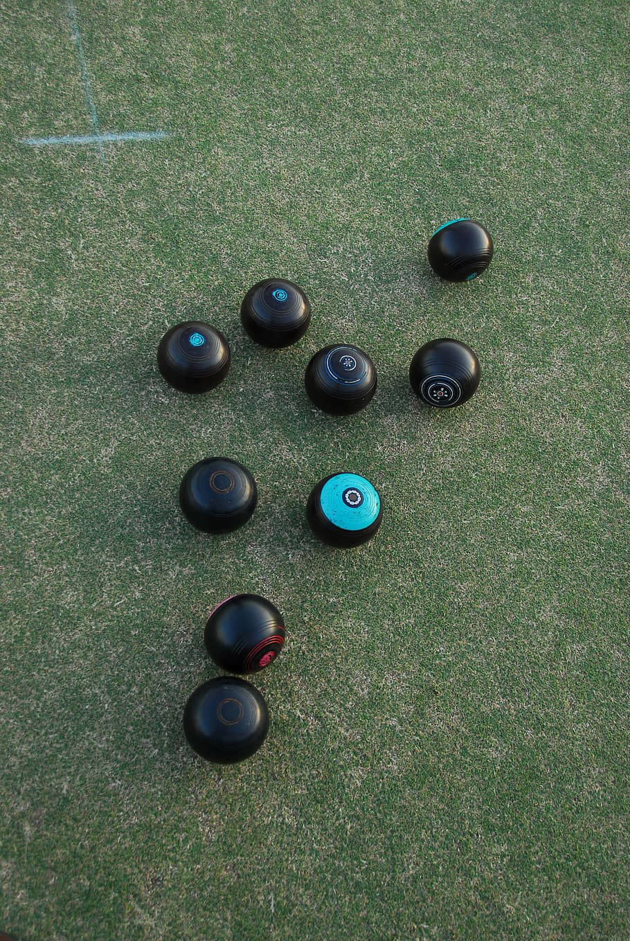 Black and teal lawn bowls on green artificial turf for outdoor game.