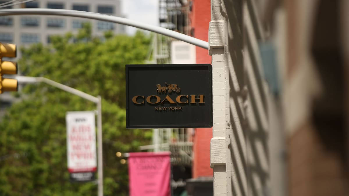 城市環境中磚砌建築上的黑色Coach New York商店招牌。