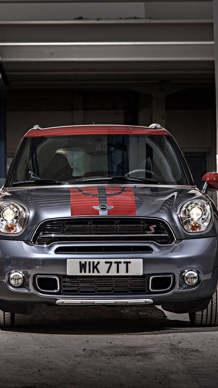 銀色Mini Countryman S，帶紅色車頂和賽車條紋，停放在車庫中。