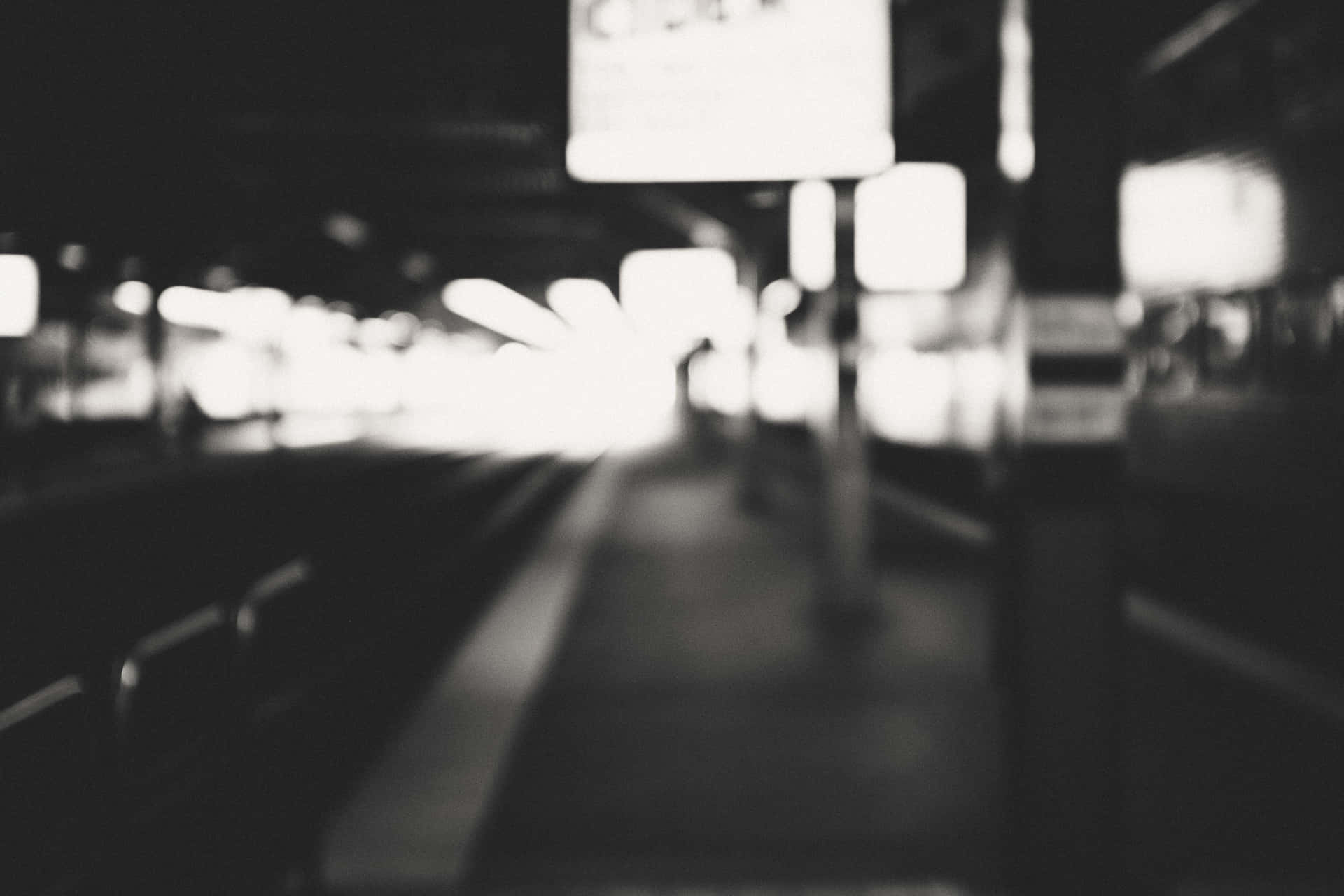 夜晚有發光燈光的模糊黑白火車站月台。