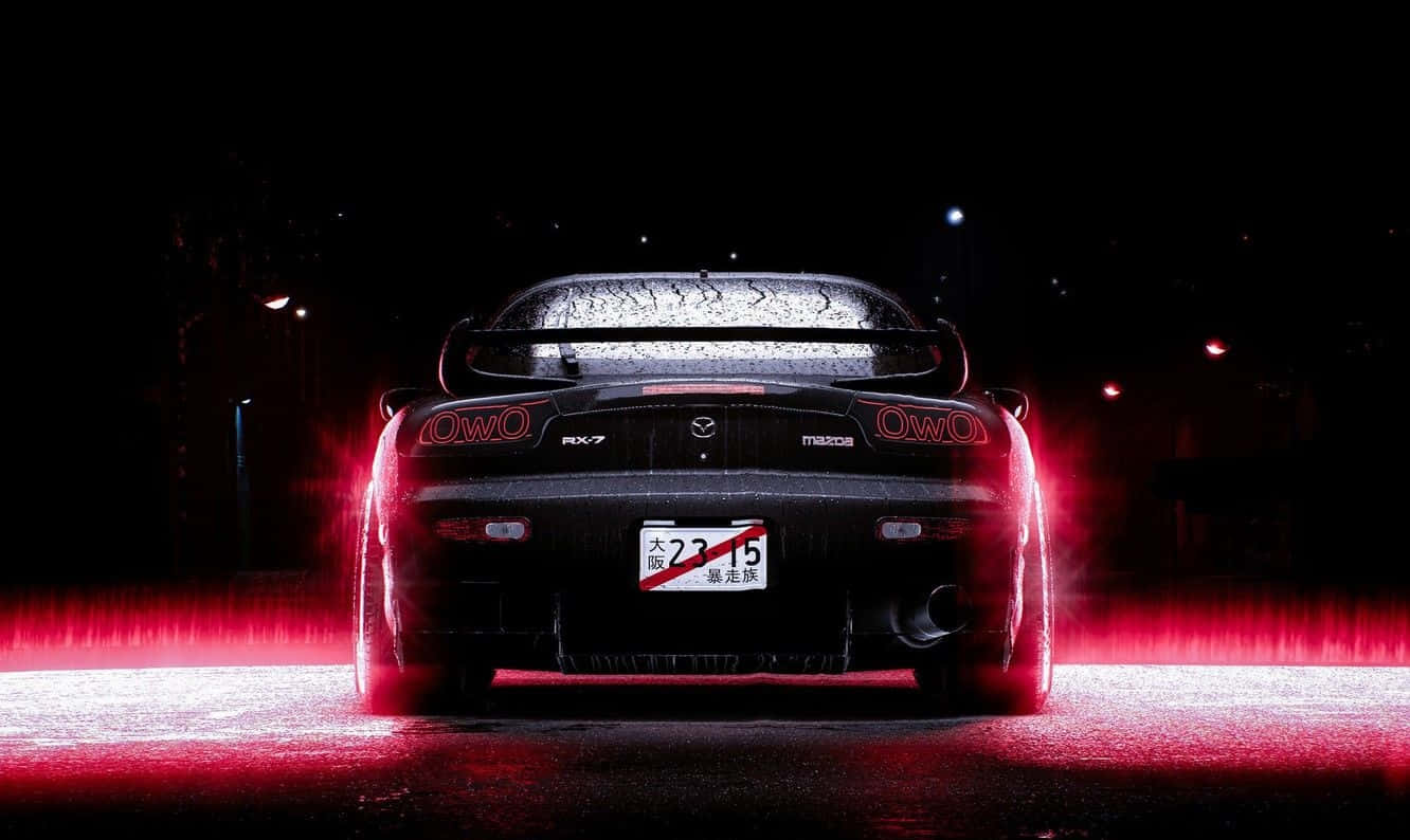 黑色Mazda RX-7跑車在潮濕夜街上發出紅色尾燈光芒。