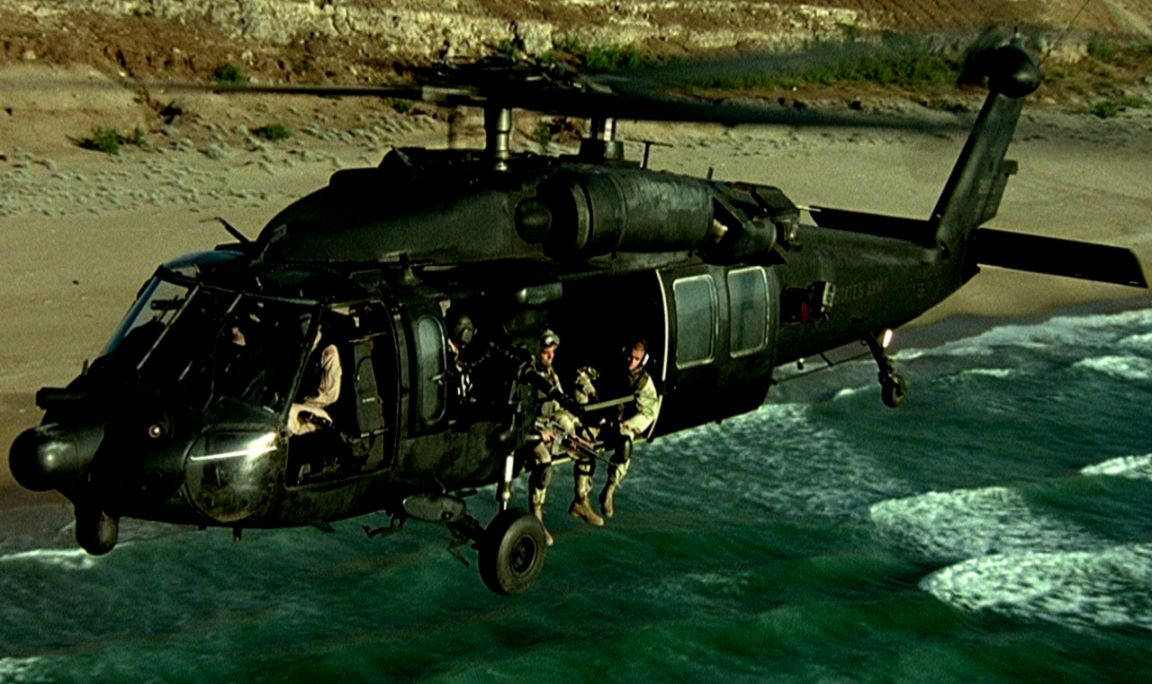 黑色軍用直升機及士兵沿繩索降落到沙灘附近的海中