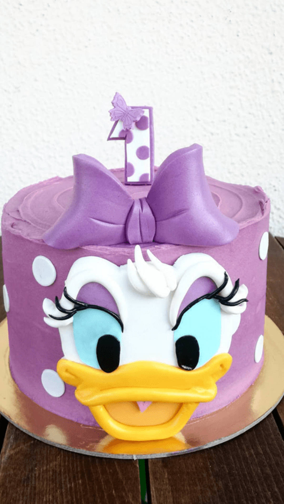 紫色黛絲鴨生日蛋糕，有白色圓點和數字一蠟燭。