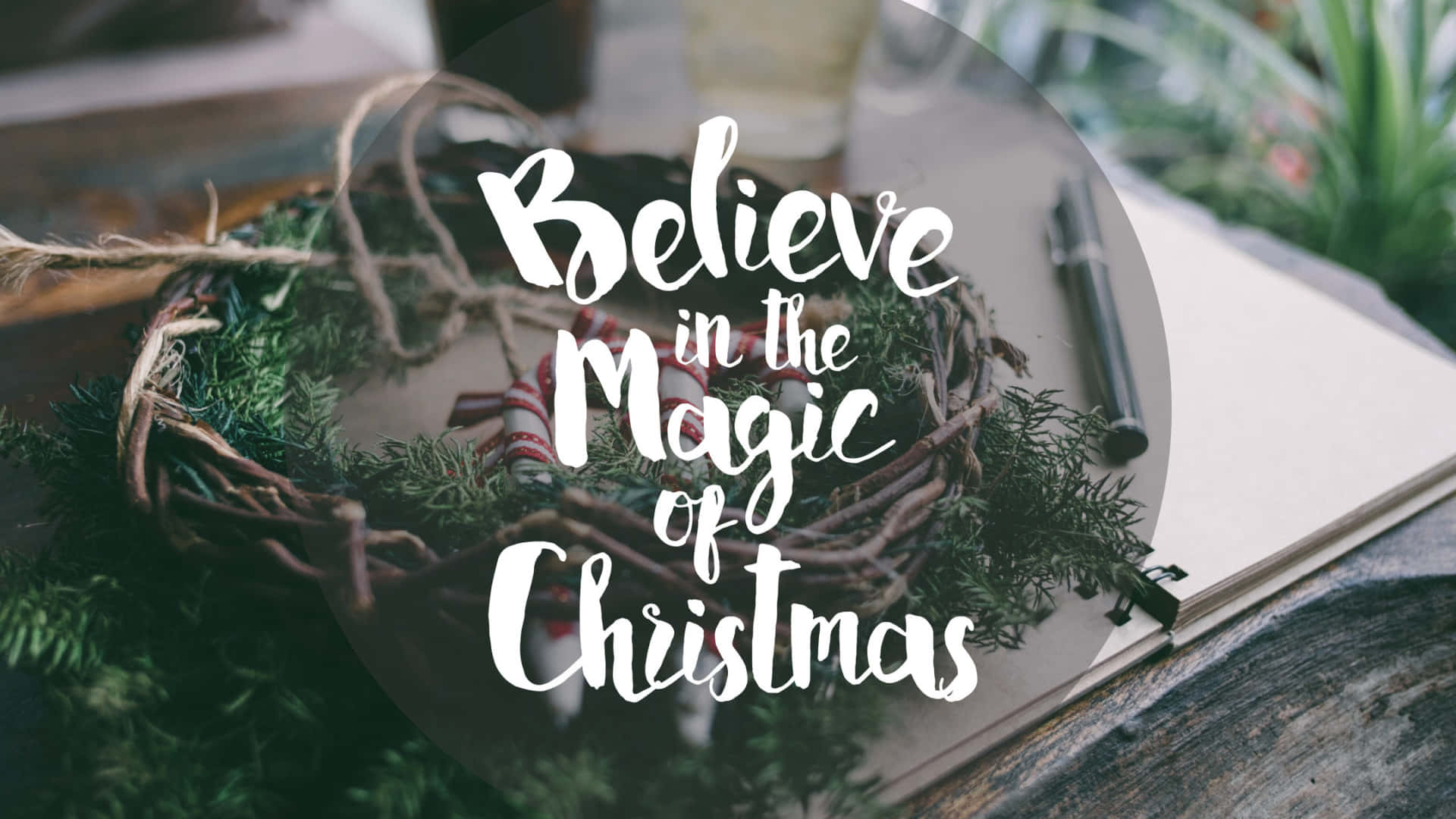 聖誕花環和筆記本在木桌上，帶有「Believe in the Magic of Christmas」文字疊加。