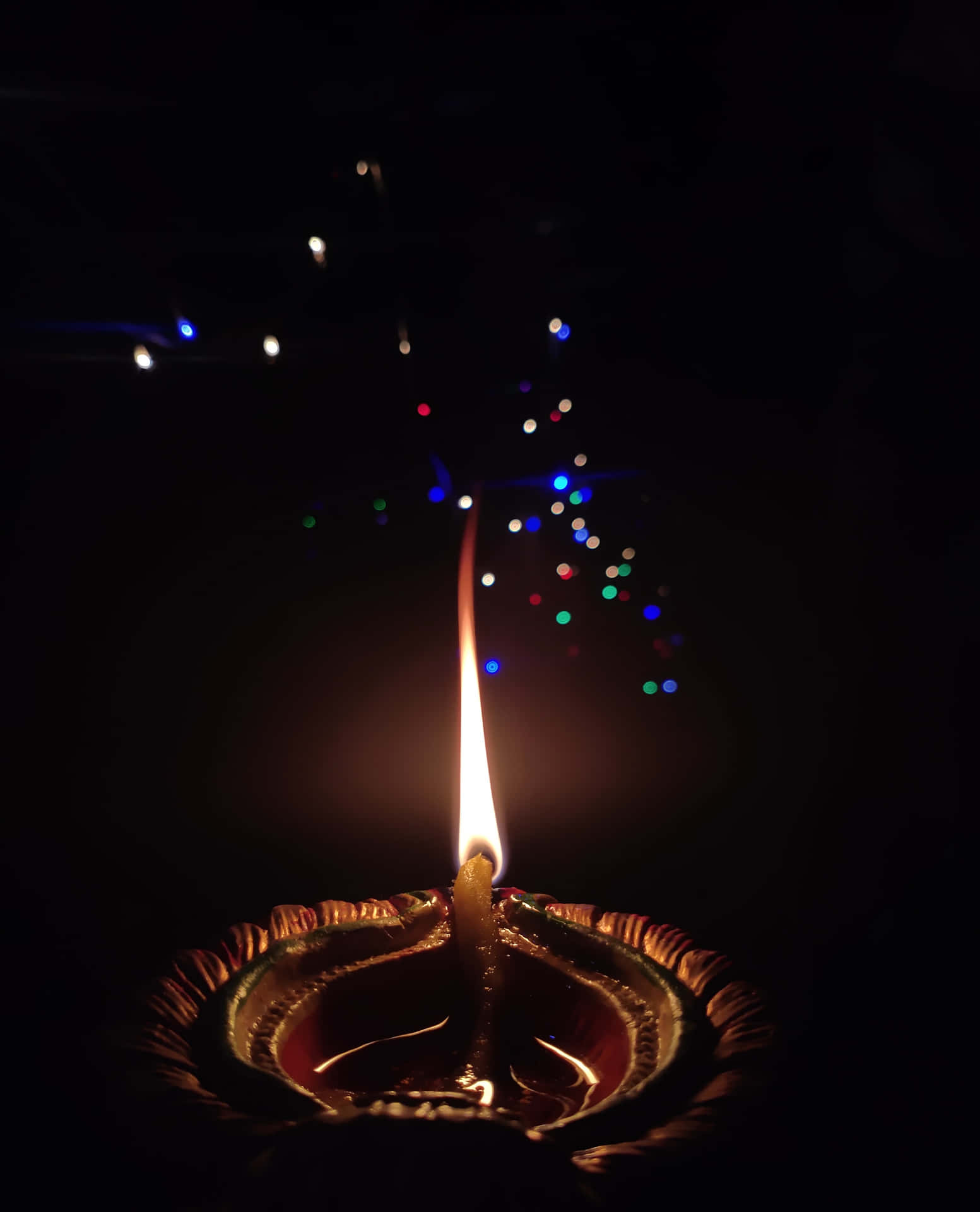 一盞點燃的迪亞燈燭，背景有彩色燈光。