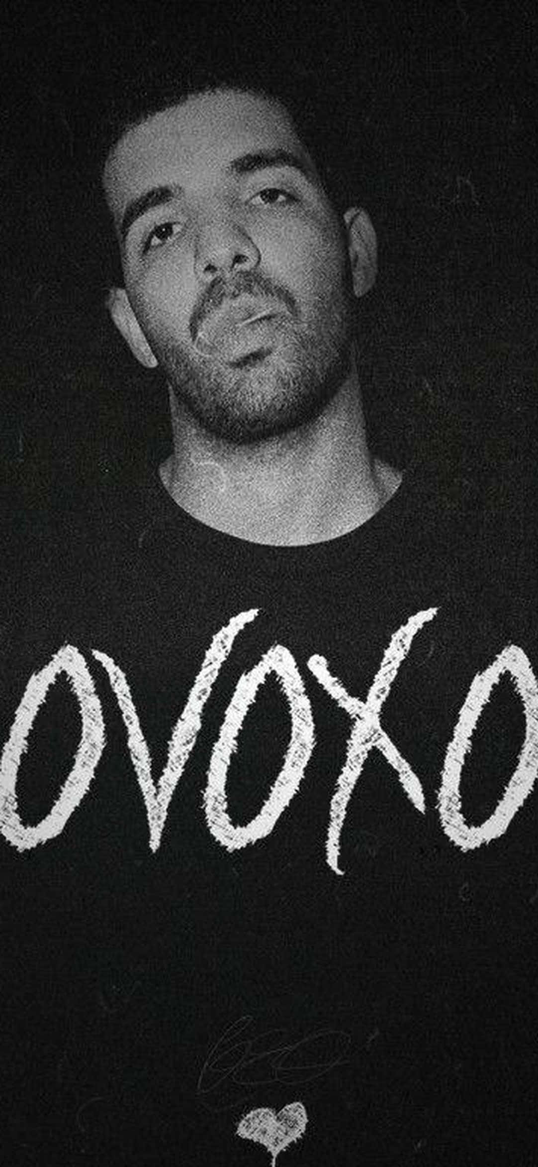 Drake 身穿黑色襯衫，帶有白色 OVOXO 文字和簽名。
