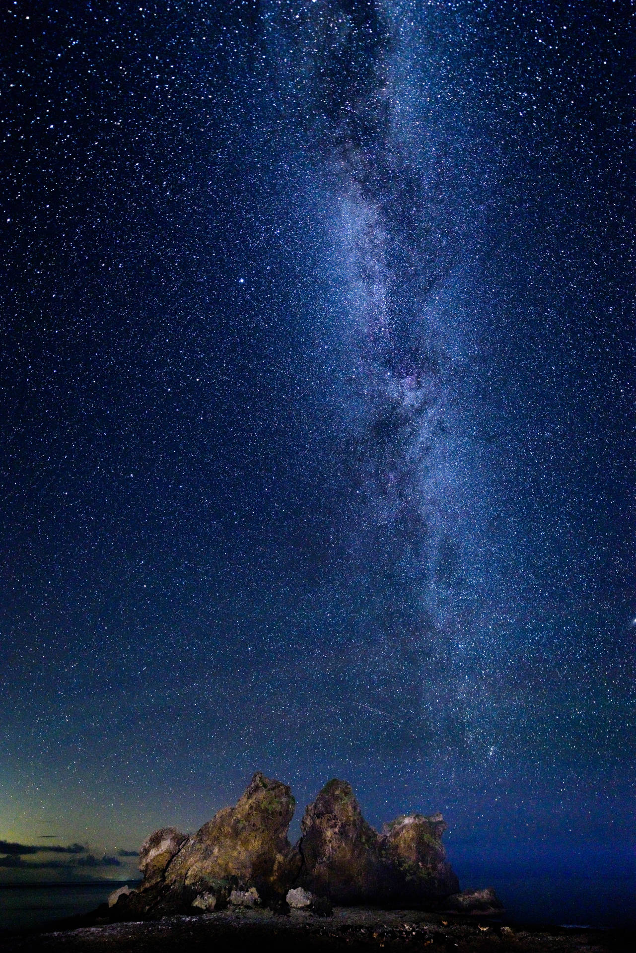 銀河系在星空下照耀著岩石海岸線