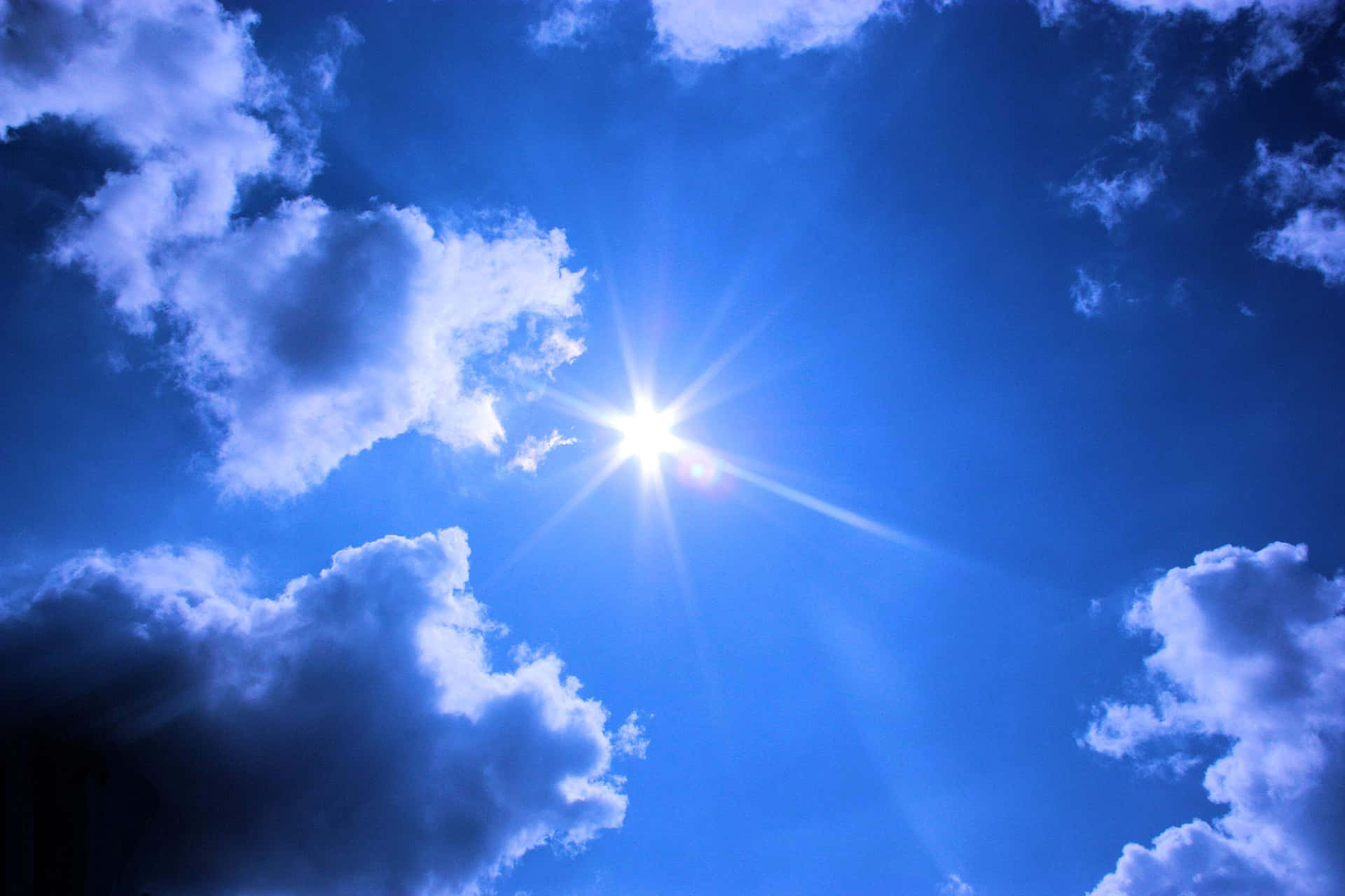 太陽在清澈的藍天中透過白雲明亮地照耀。
