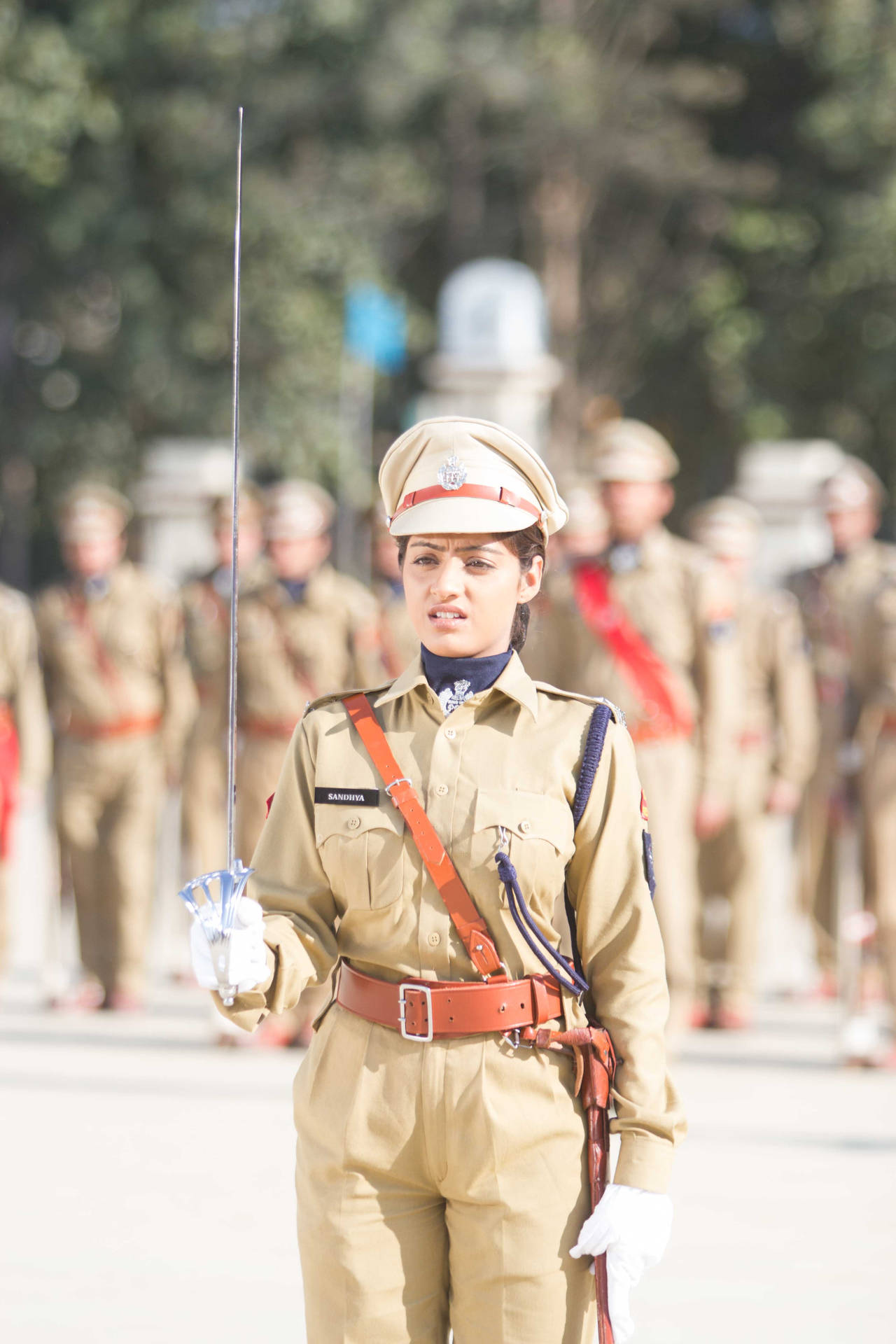 身穿卡其色制服的女兵在戶外軍事儀式中持劍。