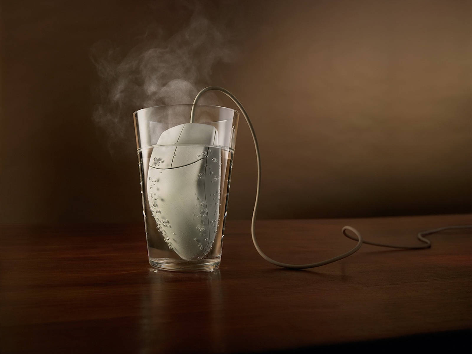 鼠在玻璃杯內與水 壁紙 — 一隻白色電腦滑鼠浸喺一杯水入面，散發出蒸氣，背景係溫暖嘅棕色。