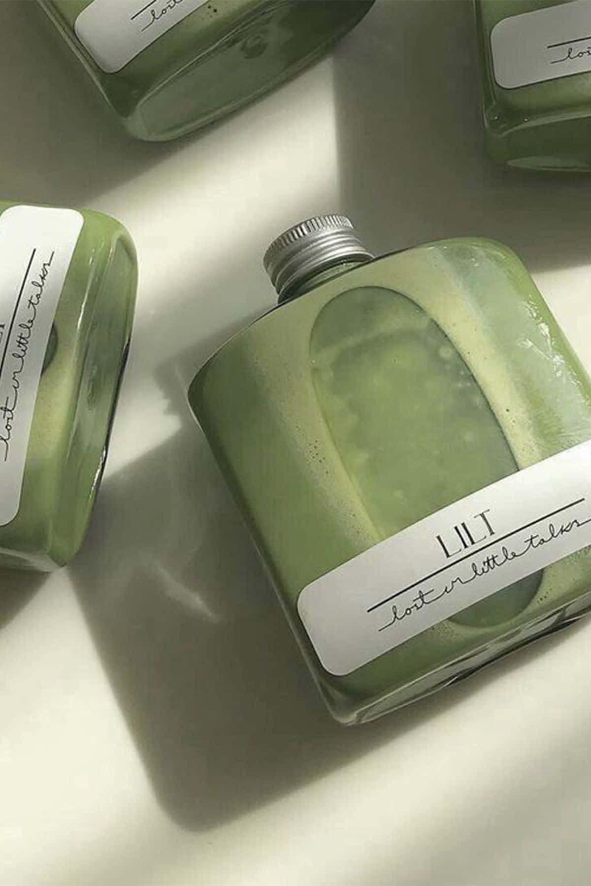 四個帶有手寫標籤的綠色玻璃瓶在白色表面上。