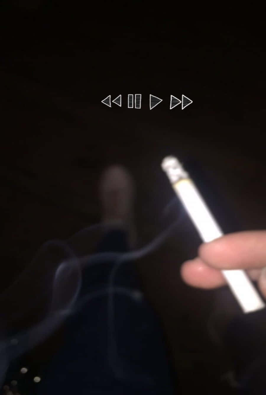 一隻手拿著一支點燃的香煙，煙霧在黑暗中升起。