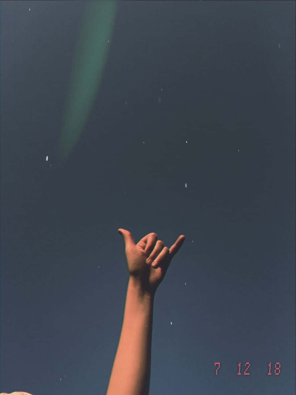 手在藍天背景下做出夏卡手勢，帶有鏡頭光暈