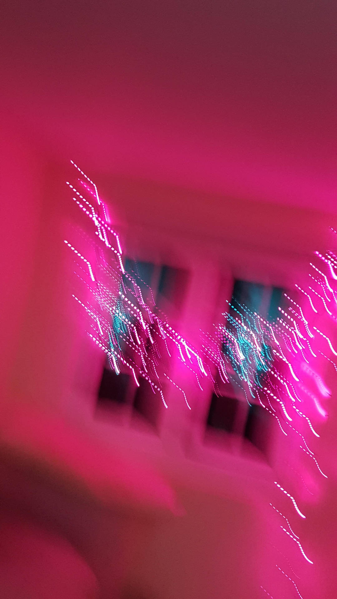 粉紅色和青色光條在昏暗的房間中模糊地劃過窗戶。
