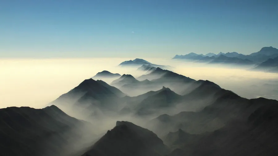 黎明時分,山峰從雲海中浮現,天空清澈湛藍