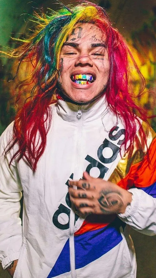 擁有彩虹頭髮和彩色牙齒的人,穿著白色Adidas外套。
