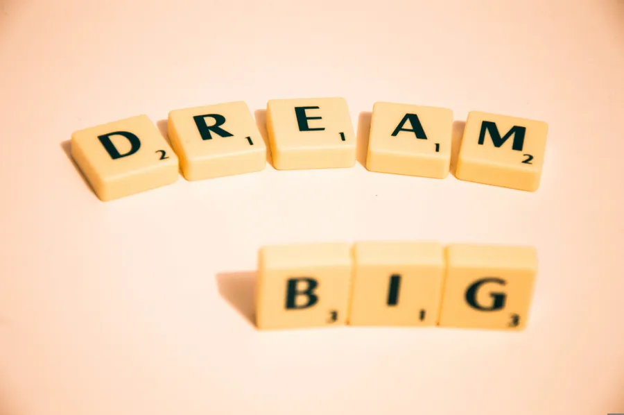 在溫暖背景上拼出dream big的Scrabble瓷磚