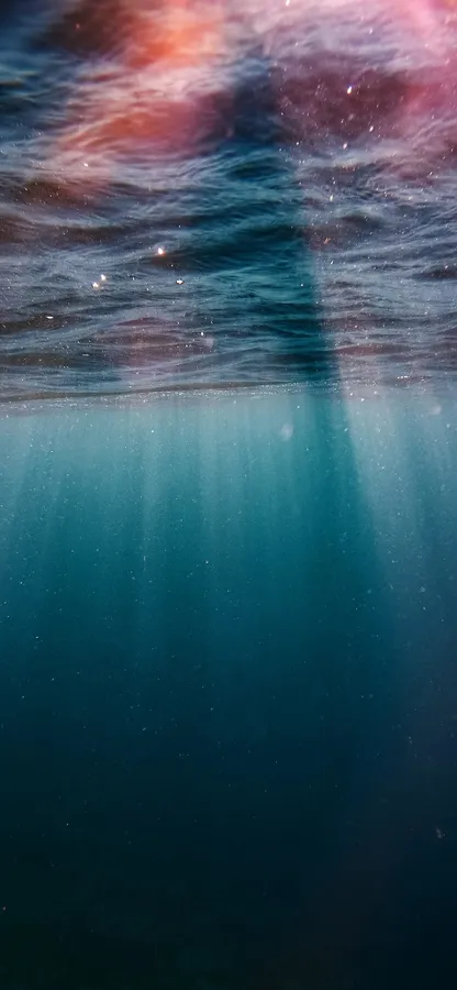 陽光穿過水面,照耀著宇宙天空和深藍色水下場景。