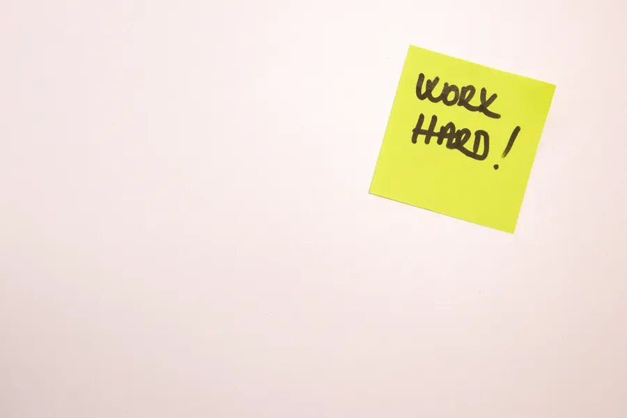 黃色便利貼,上面有手寫訊息work hard,純色背景。