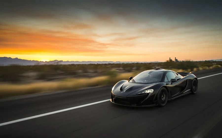 黑色McLaren超級跑車在日落時分在沙漠高速公路上疾馳。