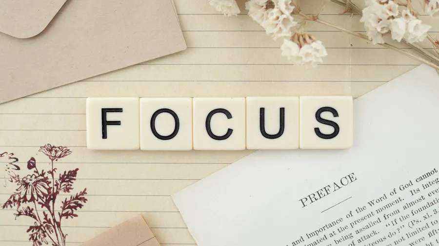 奶油色瓷磚在書桌上拼出focus,配有乾花和一本打開的書。