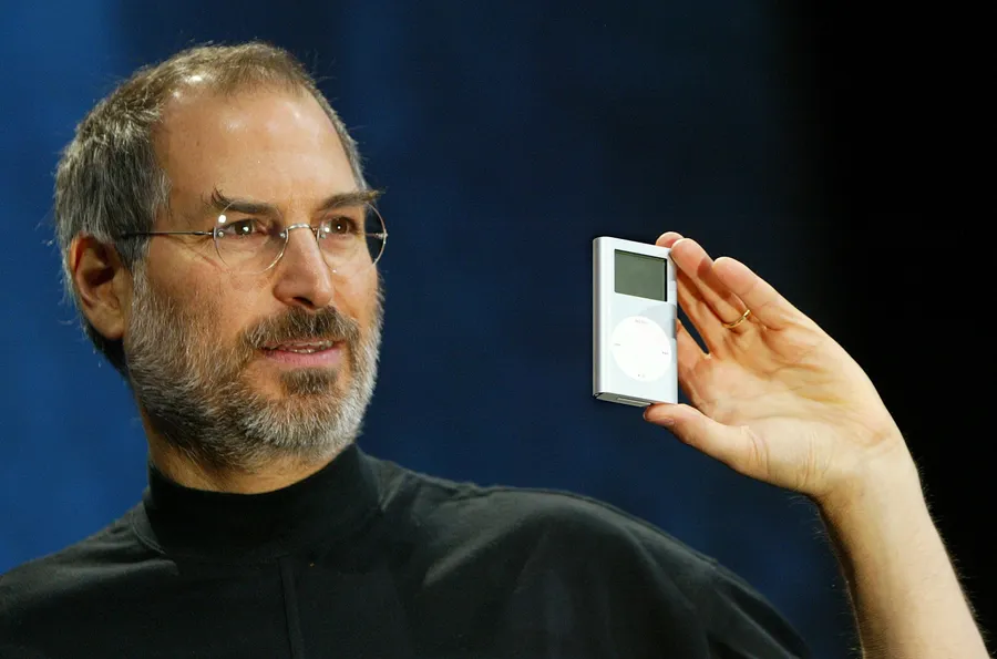 Steve Jobs 在藍色背景的舞台上展示白色 iPod。