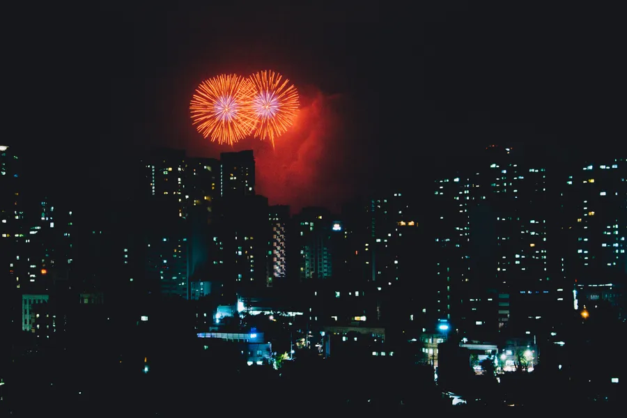 煙火在夜間城市上空綻放,下方是燈火通明的建築物。