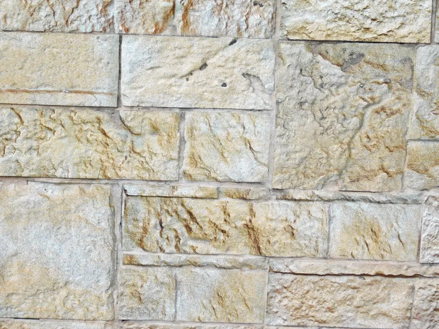 米色同棕褐色石牆嘅特寫,帶有粗糙紋理嘅石塊。
