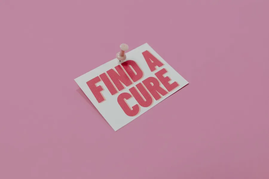 一張粉紅色卡片,上面釘有訊息「Find a Cure」,背景為粉紅色。