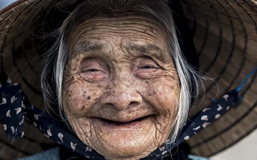 一位笑容滿面的老婦人戴著傳統的圓錐形帽子。