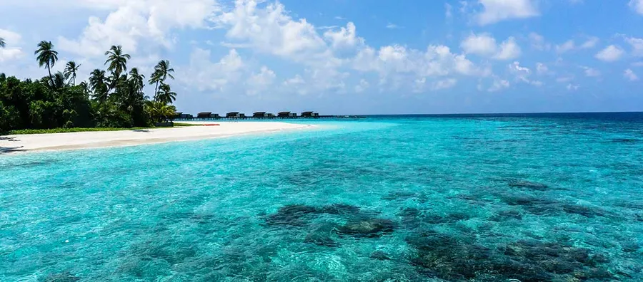 陽光明媚的天空下,擁有碧綠海水和水上平房的熱帶海灘。