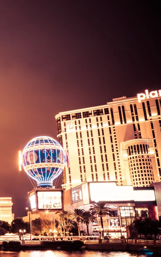 夜間點亮的 Planet Hollywood Resort,帶有發光的熱氣球雕塑和棕櫚樹。