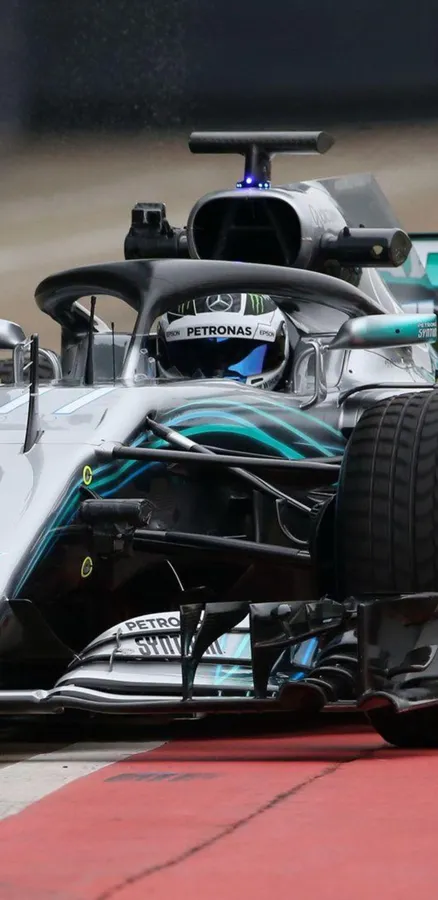 F1賽車在賽道上高速行駛,帶有紅色路緣石和輪胎水花。