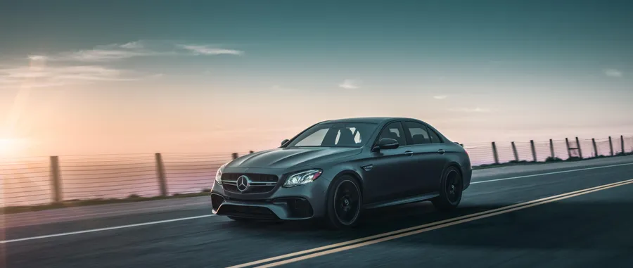 灰色 Mercedes 房車在日落時分沿海岸公路疾馳