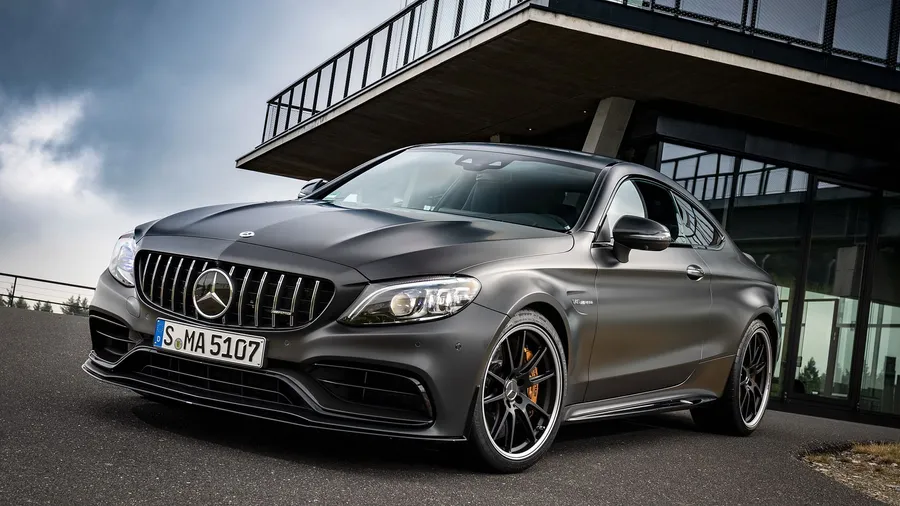 啞光灰色Mercedes-AMG C63 S Coupe停放在現代玻璃建築下。