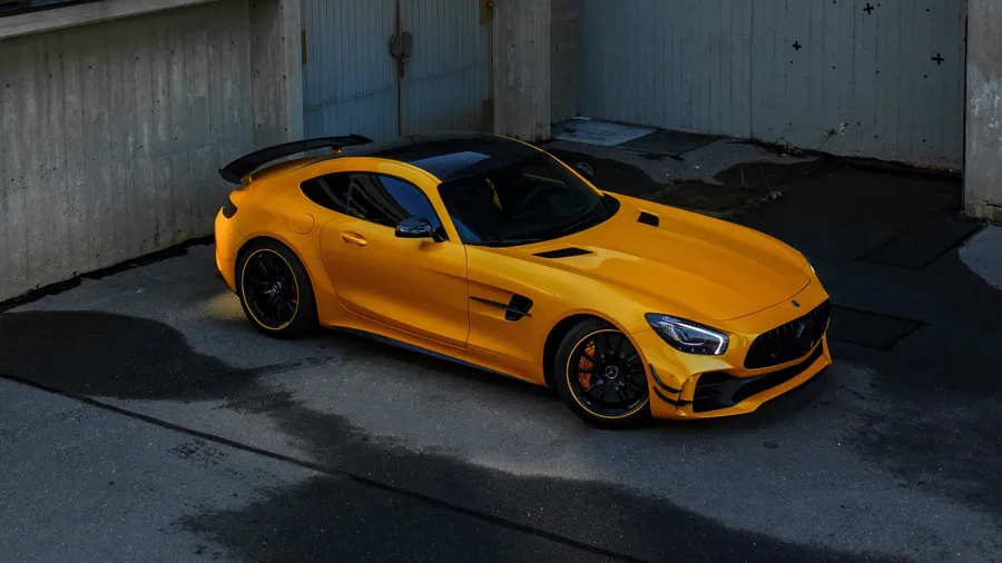 黃色 Mercedes-AMG GT R 跑車在混凝土車庫中,地面有水窪。