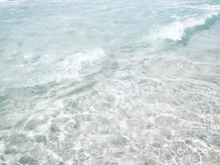 清澈藍綠色海水中翻滾著白色泡沫的溫柔海浪。