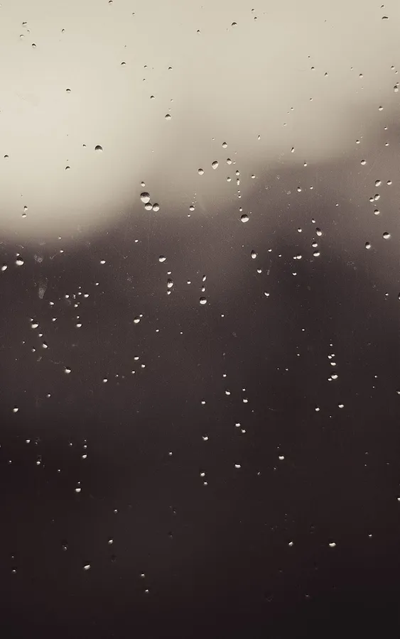 窗上的雨滴,背景是模糊的灰色天空。