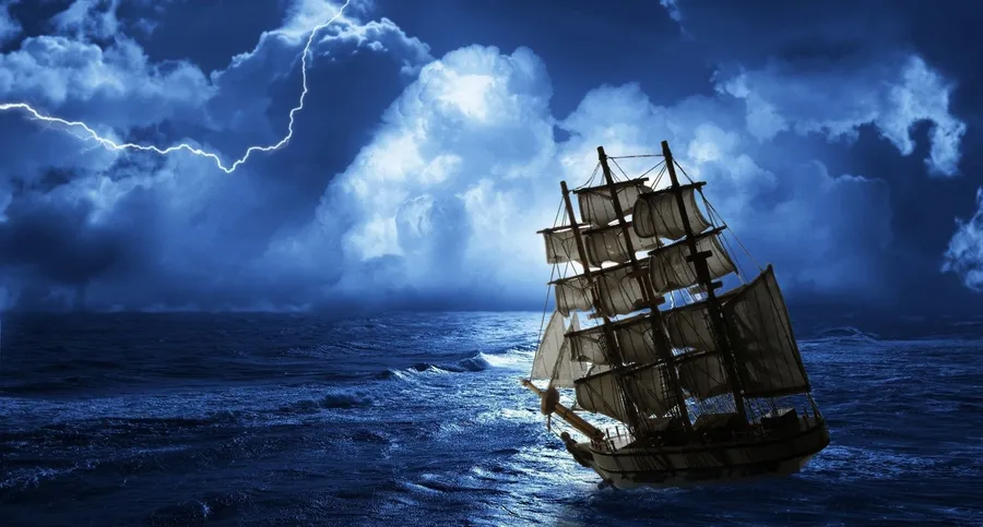 夜間暴風雨海洋中的帆船,伴有閃電和月光。
