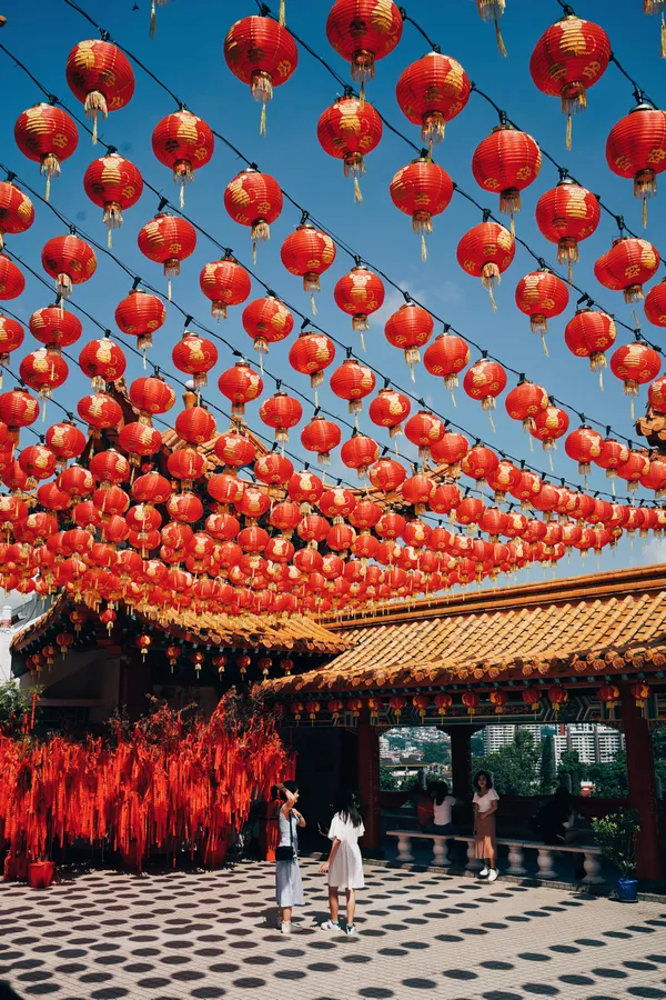 紅色燈籠掛在中國節日場地上方,下方有遊客。