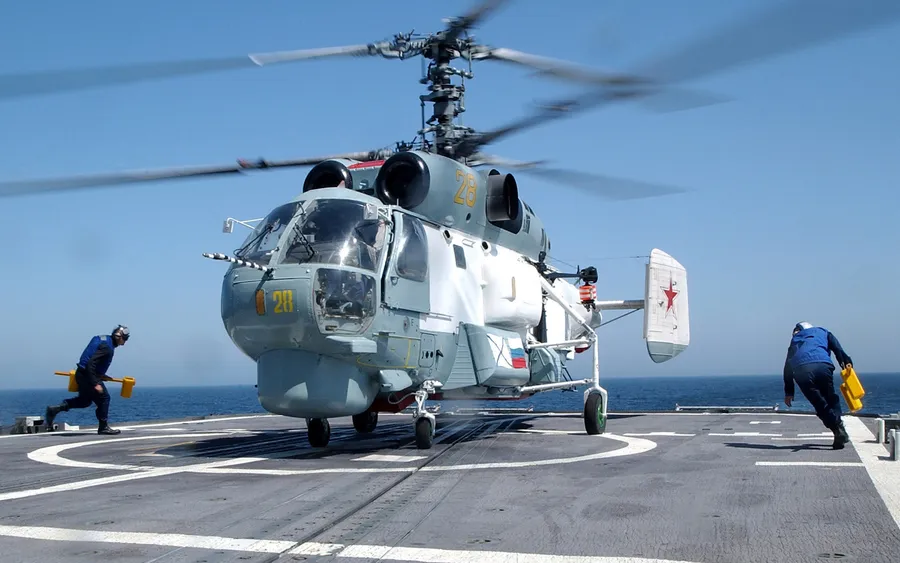 軍用直升機在航空母艦甲板上,機組人員引導它。