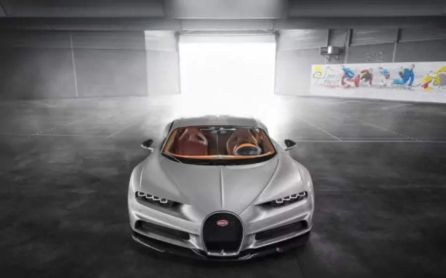銀色Bugatti Chiron喺現代工業風車庫中,帶有強烈背光。