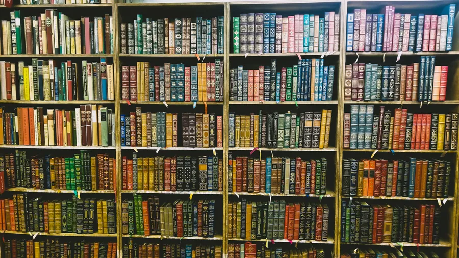 一排排帶有華麗書脊的復古書籍放在圖書館的木製書架上。